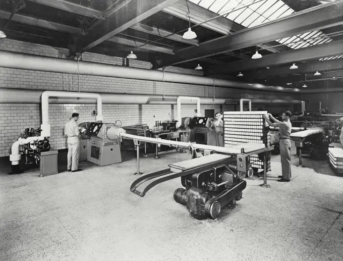 Vintage photograph. One of a battery of mechanical freezers at work turning out an endless bar of pure ivory soap. The white pipes carry the liquid soap to a high speed mixer and then on to a freezer at the Proctor and Gamble Company