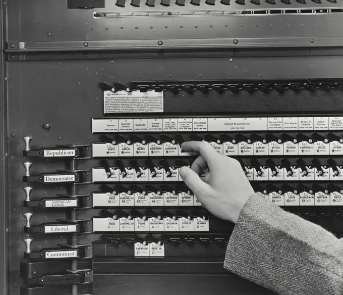 Vintage photograph. Hand pushing levers on voting machine