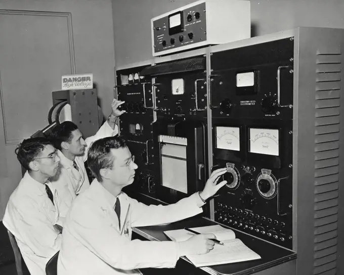 Vintage photograph. Scientists operating a mass spectrometer, an instrument which uses magnetic and electrical forces to separate isotopes