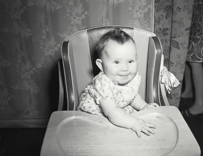 Vintage photograph. Baby in highchair.