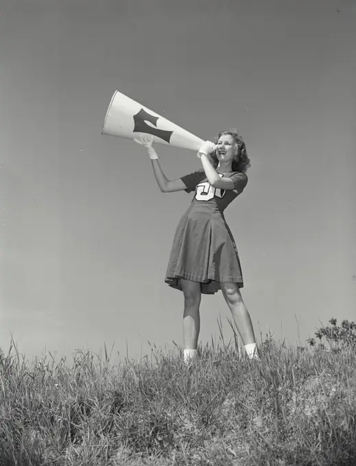 Vintage photograph. Cheerleader yelling into megaphone