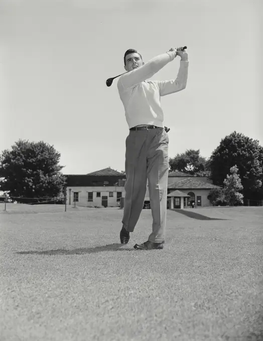 Vintage photograph. Man swinging golf club on course