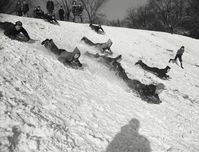 Vintage photograph. Children sledding down snowy hill