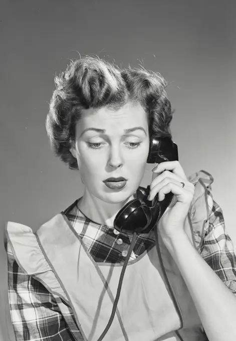 Vintage photograph. Woman in apron talking on telephone.