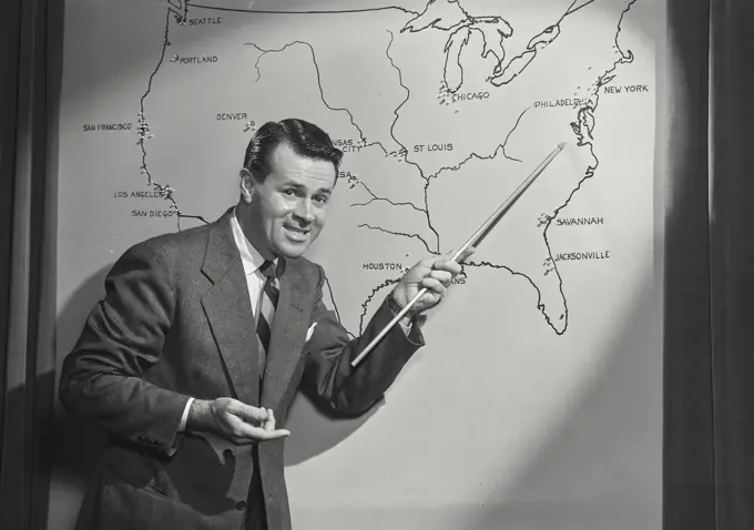 Vintage photograph. Man in suit and tie pointing at map