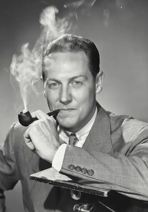 Vintage photograph. Man smoking pipe with arm on support