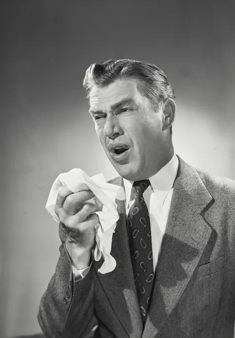 Vintage photograph. Bill Sullivan. Man in suit coughing into handkerchief.