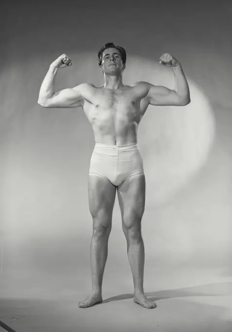 Vintage photograph. Bodybuilder flexing biceps.