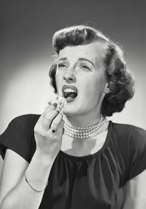 Vintage photograph. Portrait of woman in U-neck blouse with pearl necklace coughing into handkerchief