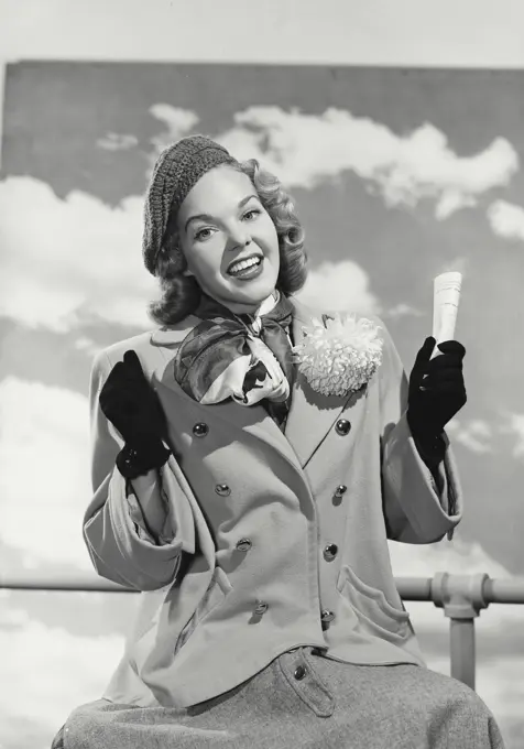 Vintage photograph. Woman in hat and coat holding paper smiling