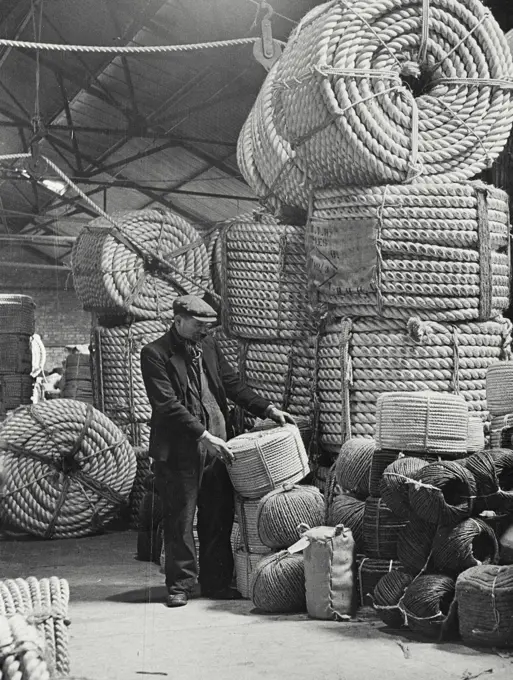 Vintage photograph. Man standing with loads of rope in factory in Belfast, Northern Ireland