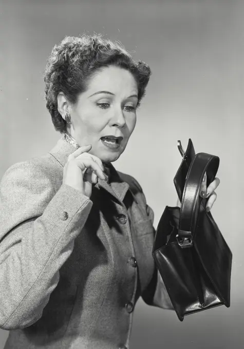 Vintage photograph. Close-up of a mature woman with shocked expression looking into empty purse