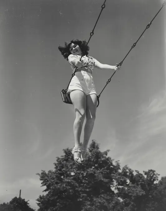 Vintage photograph. Looking up at young woman on swing