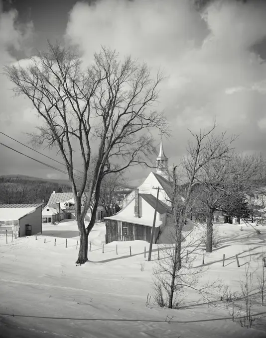 Vintage photograph. Winter at St Adele showing snow covered trees and church in distance