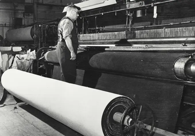 Setting the frame for an Axminster carpet. From the squared design on the roller, the colored yarns are wound onto spools ready for the loom.