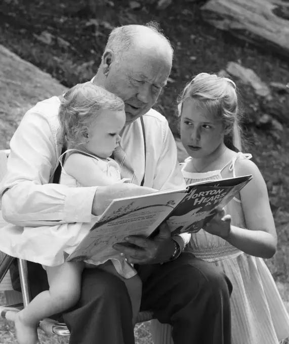 Grandfather reading a story to his two granddaughters