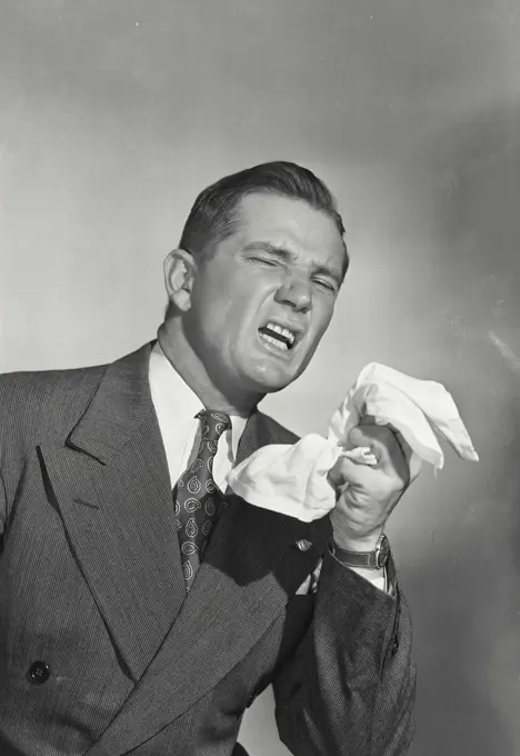 Vintage photograph. Man in suit sneezing holding handkerchief