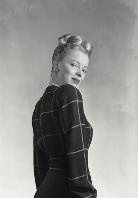 Vintage photograph. Blonde woman with hair in up style wearing dark blouse turned to side smiling