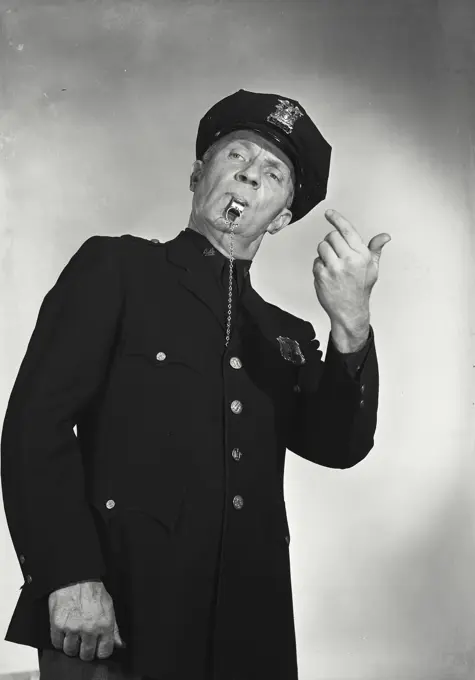 Vintage photograph. Man in police uniform with whistle in mouth making hand gesture