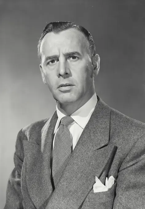 Vintage photograph. Dark Haired Businessman wearing suit and pocket square looking serious