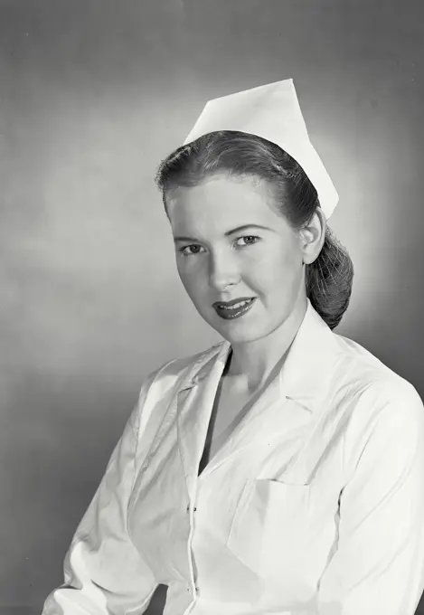 Vintage photograph. Woman wearing nurse uniform and cap with soft smile expression