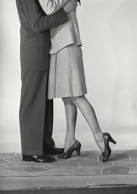 Vintage photograph. Legs of man wearing suit and trousers and woman wearing skirt and heeled shoes