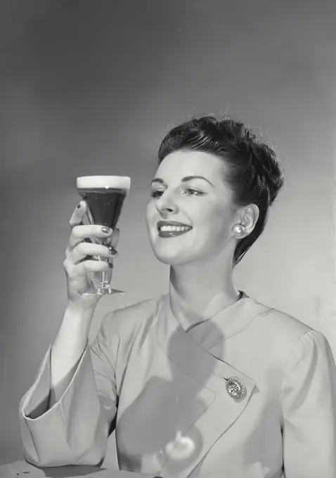 Vintage photograph. Woman staring at beer glass and smiling