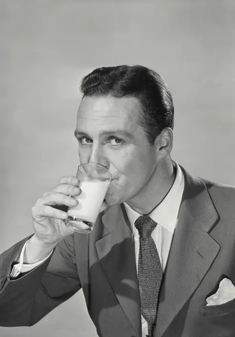 Vintage photograph. Man in suit drinking glass of milk