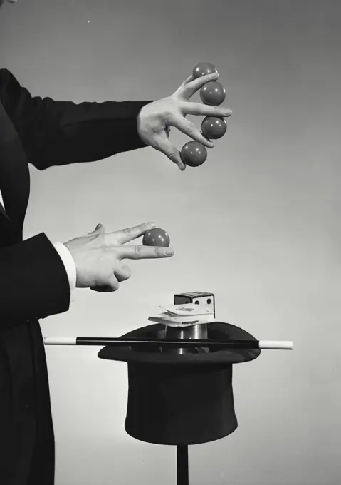 Vintage photograph. Magician holding up five balls in between fingers