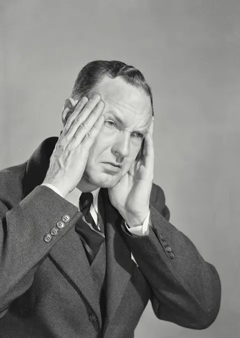 Vintage photograph. Businessman looking distressed holding hands up to head