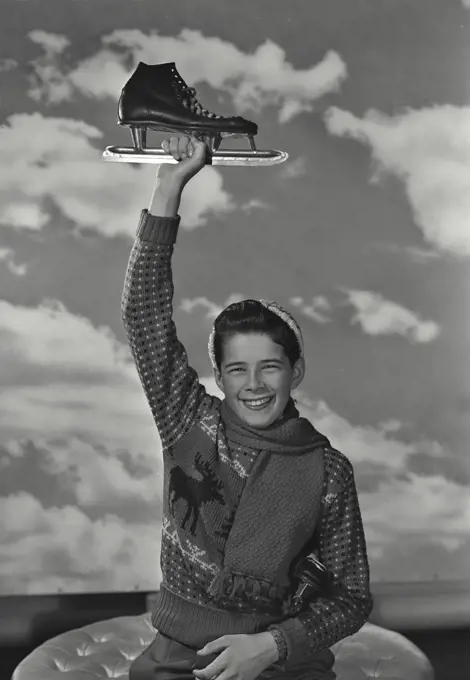 Boy in sweater holding up an ice skate