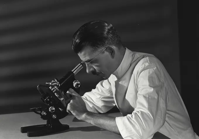 Scientist studying the slide under microscope