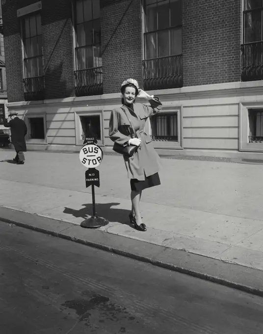 Woman in coat standing at bus stop