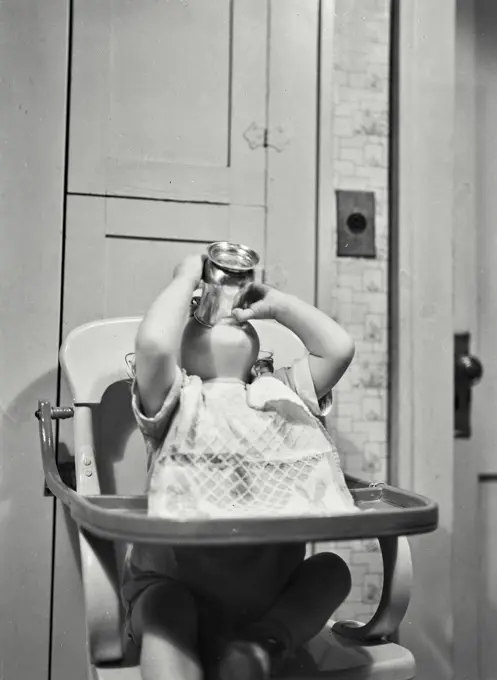 Baby girl in high chair drinking from cup