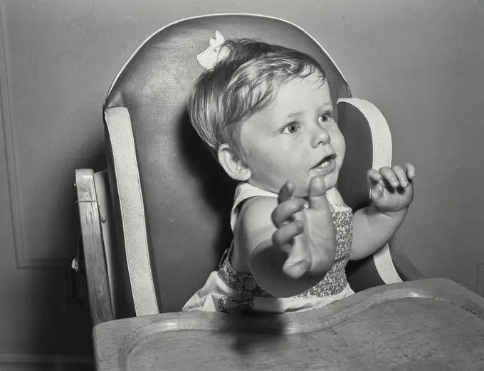 Baby in high chair reaching toward camera