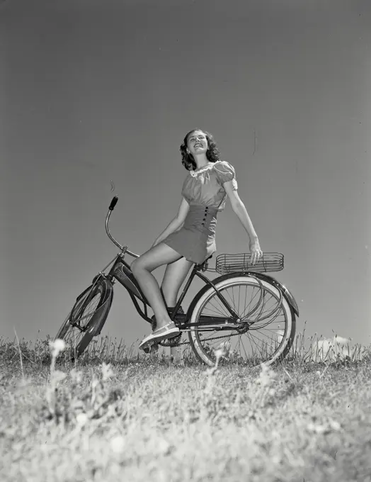 Woman on bicycle leaning back onto the basket