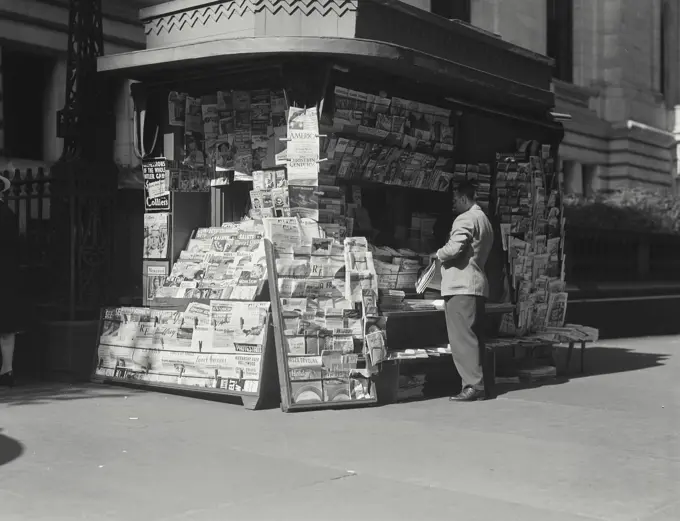 Man standing at news stand in town