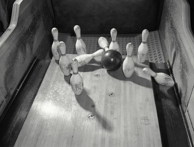 Pins being knocked down by ball at bowling alley