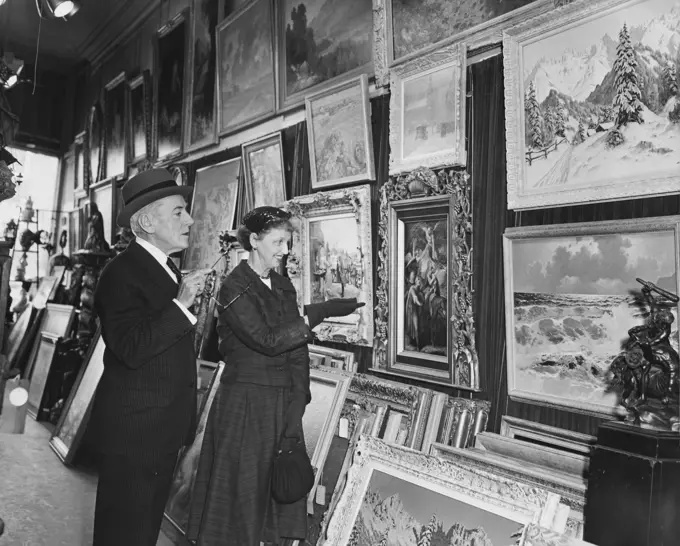 Side profile of a mature couple looking at paintings in a store