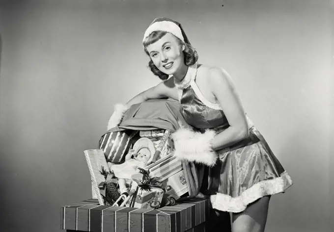 Vintage photograph. Portrait of a young woman dressed as santa dumping toys down chimney