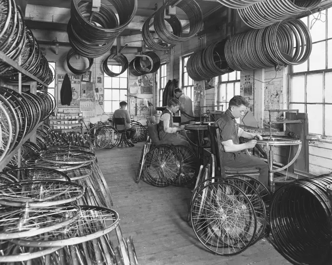 Four manual workers manufacturing bicycles in a factory