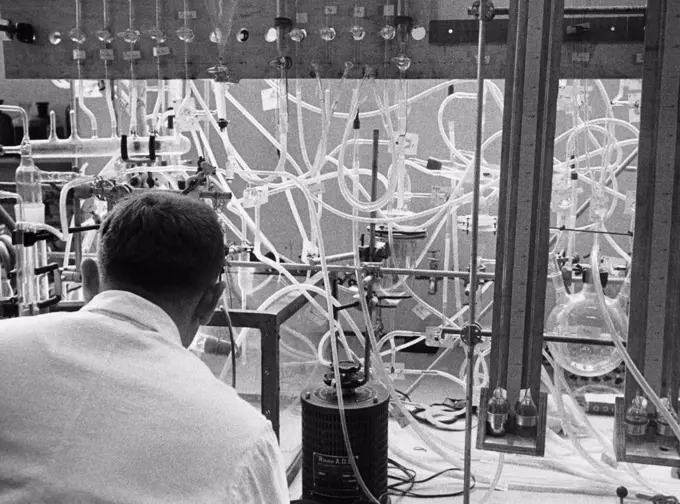 Rear view of a researcher working with experimental apparatus to disintegrate uranium in a laboratory