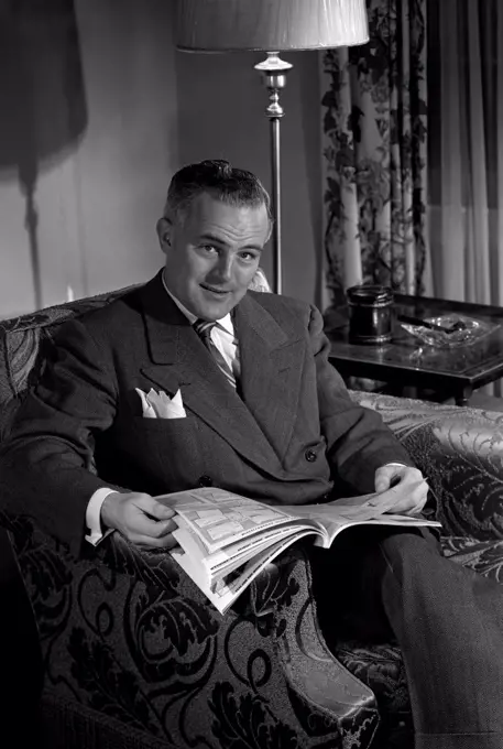 Portrait of mature man sitting in armchair, browsing comic