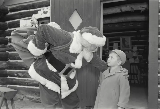 Vintage Photograph. Side profile of Santa Claus talking with boy