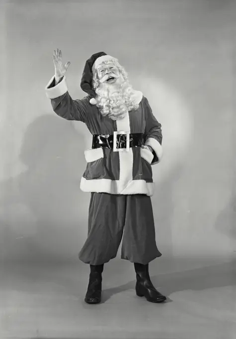 Vintage photograph. Close-up of man in Santa Claus costume smiling with hand raised