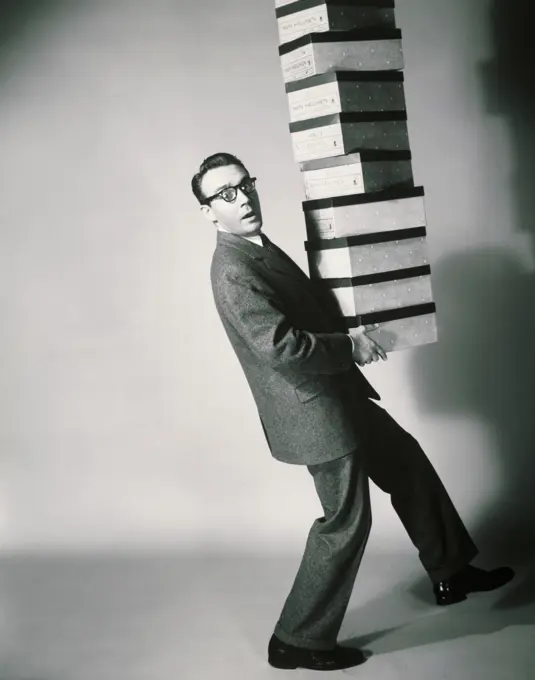 Side profile of a salesman carrying a stack of shoeboxes