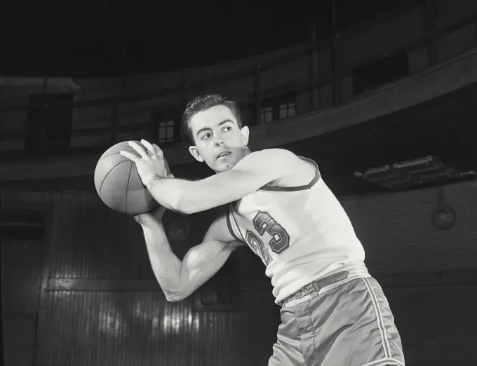 Vintage Photograph. Basketball player holding ball away from player off camera