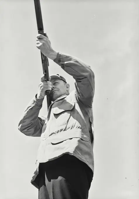 Vintage Photograph. Man in coat with shotgun aiming shot