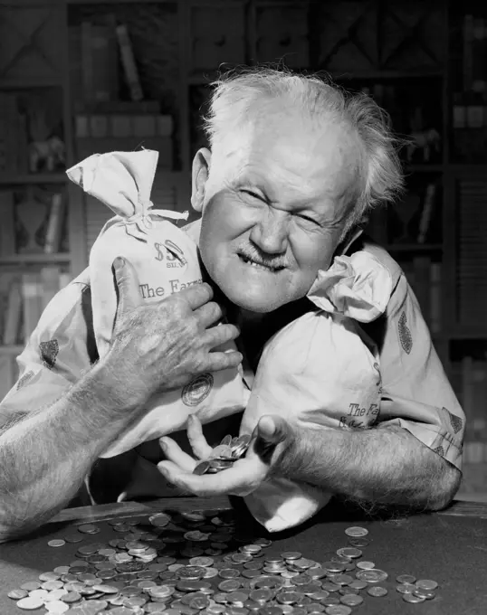 Close-up of a senior man holding two bags of coins