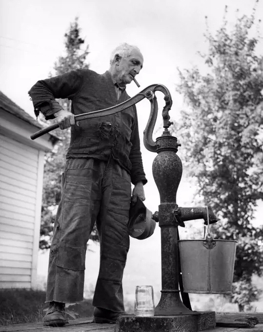 USA, New Hampshire, Lyme, senior man pumping water in garden